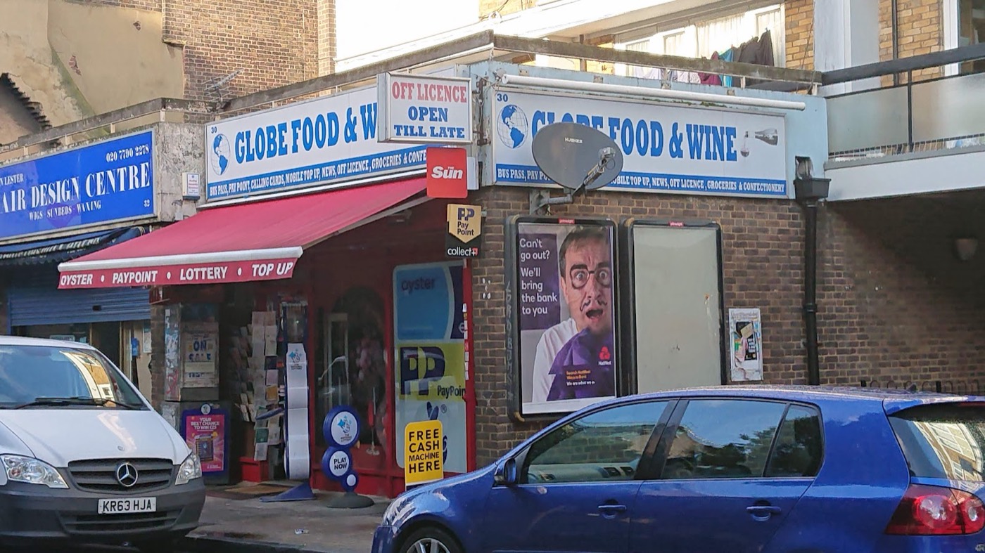 The Globe Food and Wine shopfront on Globe Road, Bethnal Green: blue fascia, red awning reading Oyster, PayPoint, Lottery and Top Up, off licence open till late.